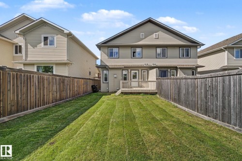 Expansive backyard featuring a manicured lawn, full wood privacy fencing, and a wooden deck - 5205 168 Avenue Nw, Edmonton, AB 
