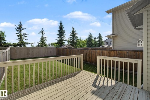 Spacious backyard featuring a wooden deck with railing, natural wood privacy fencing, and a manicured lawn - 5205 168 Avenue Nw, Edmonton, AB 