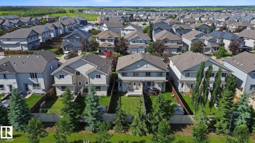 Rear exterior with a wood deck, manicured lawn, and mature evergreen trees - 5205 168 Avenue Nw, Edmonton, AB 