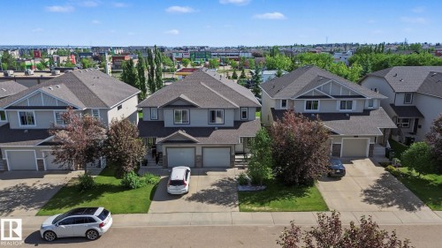 Contemporary two-story residence featuring a gray exterior with white trim, a dark shingled roof, a double attached garage, and a concrete driveway - 5205 168 Avenue Nw, Edmonton, AB 