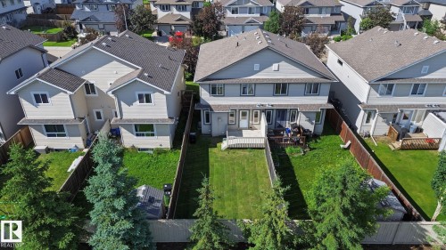 Expansive fenced backyard featuring a manicured lawn, mature evergreen trees, and a private wood deck - 5205 168 Avenue Nw, Edmonton, AB 
