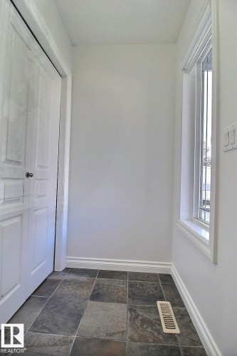 Tiled flooring throughout with a full-height window and baseboard trim - 5205 168 Avenue Nw, Edmonton, AB 