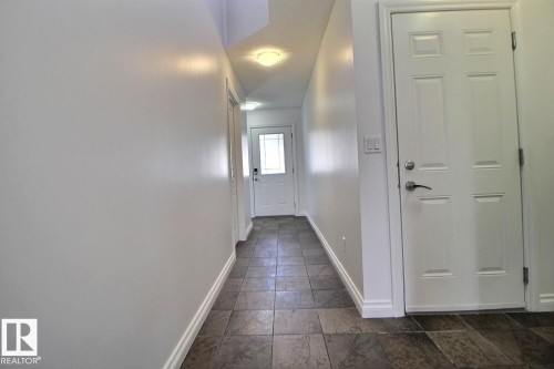 Hallway with tiled flooring and white paneled doors - 5205 168 Avenue Nw, Edmonton, AB 