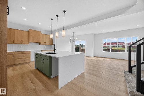 Kitchen featuring wood-finish cabinetry, a large center island with a waterfall countertop, and pendant lighting - 205 Hampshire, Sherwood Park, AB 