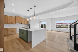 Kitchen featuring wood-finish cabinetry, a large center island with a waterfall countertop, and pendant lighting - 