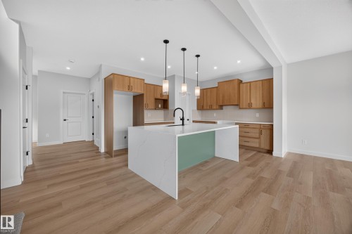 Open-concept kitchen with wood-finish flooring, light wood cabinetry, quartz waterfall island, and recessed lighting - 205 Hampshire, Sherwood Park, AB 