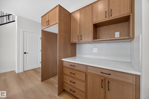 Wood-finish cabinetry with black hardware, white countertops, and a white mosaic tile backsplash - 205 Hampshire, Sherwood Park, AB 