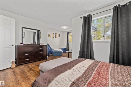 Wood-finish flooring throughout, white interior doors, and a window with white trim - #63 501 Youville Dr E Nw, Edmonton, AB 