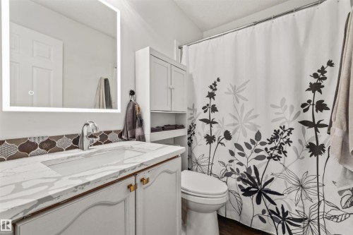 White vanity with gold-tone hardware, rectangular undermount sink, quartz countertop, and mosaic tile backsplash - #63 501 Youville Dr E Nw, Edmonton, AB 