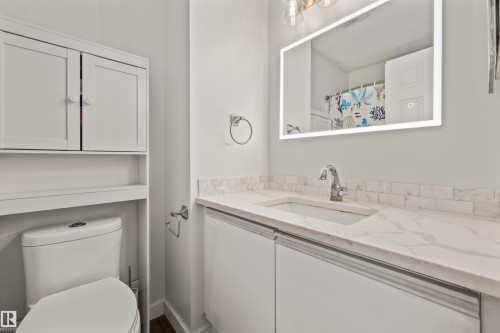 White vanity with integrated sink, stone-finish countertop, and subway tile backsplash - #63 501 Youville Dr E Nw, Edmonton, AB 