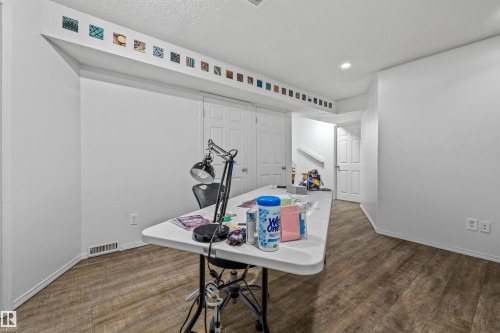 Recessed lighting illuminates the wood-finish flooring and white walls, complemented by white paneled doors and built-in closet storage - #63 501 Youville Dr E Nw, Edmonton, AB 