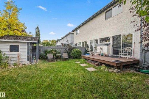 Expansive backyard featuring a wood deck, manicured lawn, and a storage shed - #63 501 Youville Dr E Nw, Edmonton, AB 