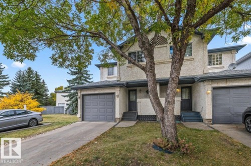 Stucco exterior with a peaked roofline, front entry door, and attached garage - #63 501 Youville Dr E Nw, Edmonton, AB 