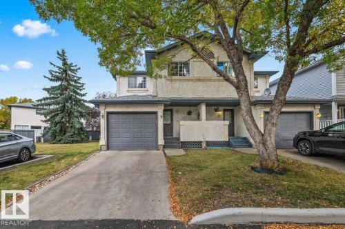 Stucco exterior with an attached single-car garage, concrete driveway, and front entryway with steps - #63 501 Youville Dr E Nw, Edmonton, AB 
