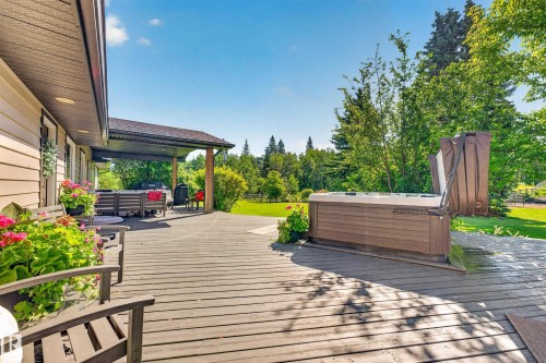 Expansive wood-finish deck featuring an outdoor spa and covered patio area - 22245 Twp Road 512, Rural Strathcona County, AB 