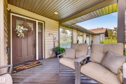 Covered front porch featuring a paneled entry door with sidelight, horizontal siding, recessed lighting, and a composite deck - 