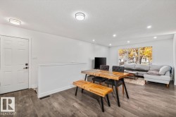 Open-concept interior featuring wood-finish flooring, recessed lighting, flush-mount ceiling fixtures, and a large picture window - 