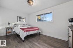 Room featuring wood-finish flooring, a horizontal sliding window with white trim, and a cage-style flush mount ceiling light fixture - 