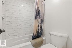 Bathtub area featuring white subway-style wall tile with gray veining and recessed wall shelving - 