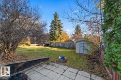 Backyard featuring a concrete paver patio, wood retaining wall, storage shed, and perimeter wood fencing - 