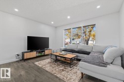 Living area featuring wood-finish flooring, recessed lighting, and a large triple-pane window - 