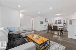 Open-concept living space featuring wood-finish flooring, white cabinetry, stainless steel appliances, recessed ceiling lighting, and a neutral color palette - 