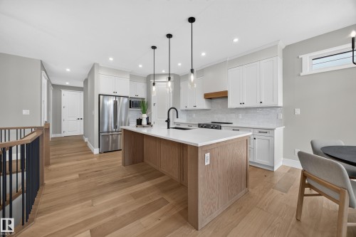 Modern kitchen with a wood-finish island, white cabinetry, stainless steel appliances, and wood-finish flooring - 209 Hampshire, Sherwood Park, AB 