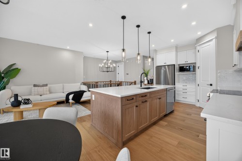 Kitchen island with wood-finish cabinetry, white countertop, and pendant lighting - 209 Hampshire, Sherwood Park, AB 