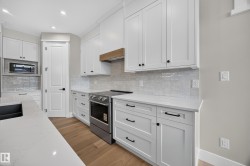 White shaker cabinetry, light-toned wood-finish flooring, stainless steel range, light-toned countertops, and a full tile backsplash - 