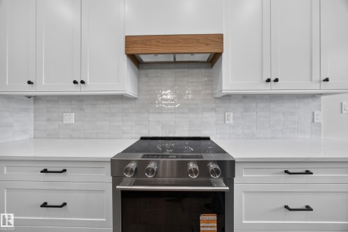White shaker cabinetry with matte black hardware, smooth white countertops, and a full tile backsplash - 209 Hampshire, Sherwood Park, AB 