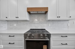 White shaker cabinetry with matte black hardware, smooth white countertops, and a full tile backsplash - 