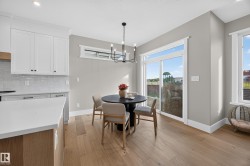 Bright dining area with wood-finish flooring, a sliding glass door, white trim, and a contemporary chandelier - 