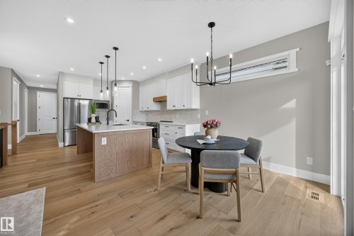 Kitchen with light wood-finish flooring, white cabinetry, a central island with a light-toned countertop, and stainless steel appliances - 209 Hampshire, Sherwood Park, AB 