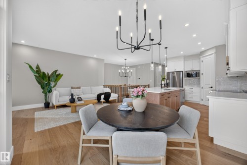 Open concept living area featuring wood-finish flooring, recessed lighting, and a modern kitchen with a center island - 209 Hampshire, Sherwood Park, AB 