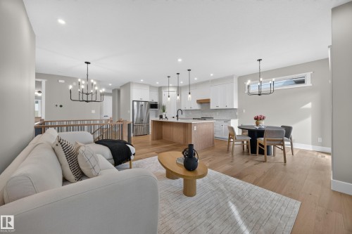 Open-concept living area with wood-finish flooring, a kitchen island, integrated stainless steel appliances, and a modern chandelier - 209 Hampshire, Sherwood Park, AB 