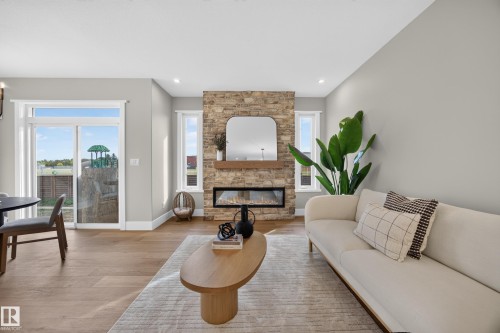 Stone-clad fireplace with built-in electric insert, wood-finish mantel, and flanking windows - 209 Hampshire, Sherwood Park, AB 