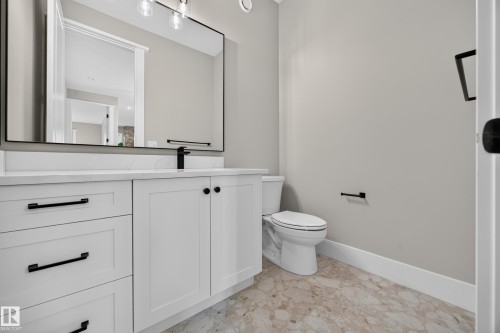 White vanity with black hardware, white countertop, rectangular mirror, and light-toned patterned flooring - 209 Hampshire, Sherwood Park, AB 