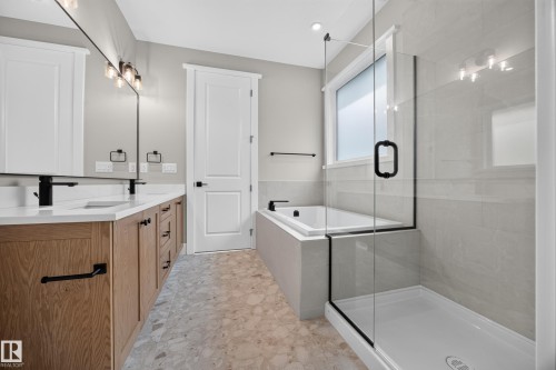 Dual vanity with wood-finish cabinetry, white countertops, and matte black fixtures - 209 Hampshire, Sherwood Park, AB 