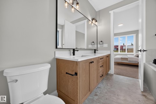 Double vanity with stone countertop, wood-finish cabinetry, and matte black fixtures - 209 Hampshire, Sherwood Park, AB 