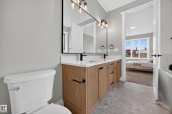 Double vanity with stone countertop, wood-finish cabinetry, and matte black fixtures - 