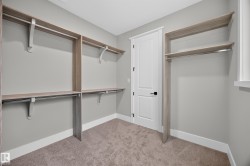 Built-in closet system featuring multiple shelves and hanging rods, neutral gray walls, and plush carpeting - 