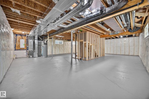 Expansive unfinished basement featuring a painted concrete floor, exposed ceiling joists, insulation, and framing for a separate room - 209 Hampshire, Sherwood Park, AB 