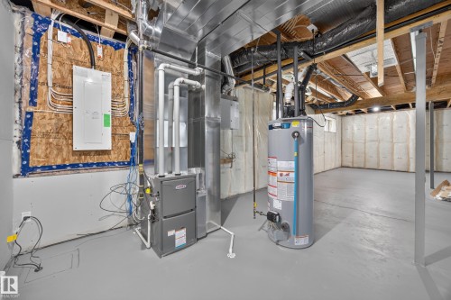 Unfinished basement with painted concrete flooring, exposed ceiling joists, and a hot water heater - 209 Hampshire, Sherwood Park, AB 