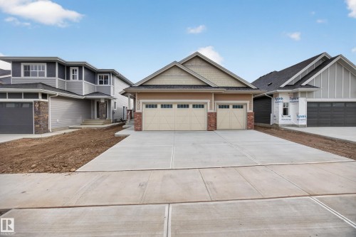 Exterior featuring a dual-bay garage, light-colored siding, brick accents, and a concrete driveway - 209 Hampshire, Sherwood Park, AB 