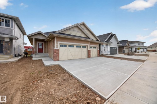 Single-story exterior with a two-car garage, concrete driveway, and red brick accenting - 209 Hampshire, Sherwood Park, AB 