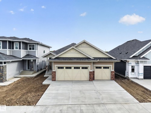 Exterior featuring a light-toned facade, decorative shake siding, and stone accents - 209 Hampshire, Sherwood Park, AB 
