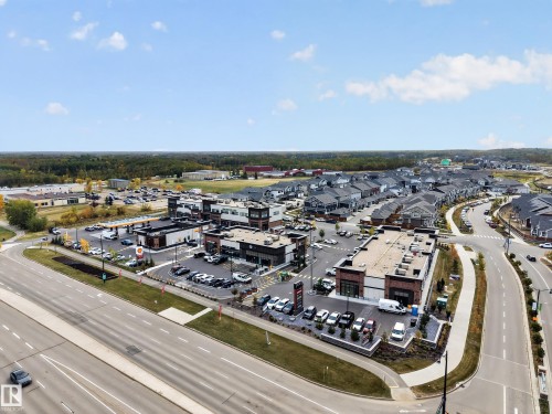 Commercial buildings with brick and dark facade accents, expansive paved parking areas, and surrounding roadways - 209 Hampshire, Sherwood Park, AB 