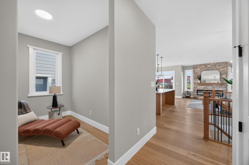 Recessed ceiling light, wood-finish flooring, stone-clad fireplace, integrated fireplace, and wood railing with black spindles - 209 Hampshire, Sherwood Park, AB 