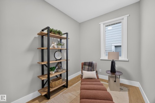 Neutral wall color, wood-finish flooring, white window trim, and a built-in shelving unit with wood shelves and a black metal frame - 209 Hampshire, Sherwood Park, AB 