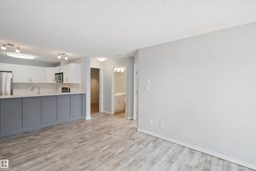 Modern kitchen featuring white upper cabinetry, grey lower cabinetry, stainless steel appliances, and track lighting - #208 16035 132 St Nw, Edmonton, AB 